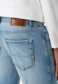 Lichtblauwe denim jeans met een leren label met het merkembleem op de achterkant. Opvallend door de stikseldetails en de gebogen zakvormen.