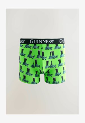 Kirkuvan vihreät boxershortsit, joissa toistuva kilpikonnakuosi, jossa kilpikonnat kantavat tuoppeja Guinnessia, ja musta vyötärönauha, jossa on valkoinen Guinness-logo.