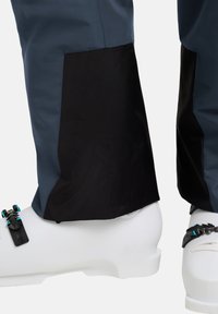 Waterdichte skibroek in donkerblauw, met zwarte nylon accenten bij de boorden en witte skischolen, met verstelbare gespen en banden.