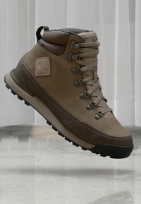 Brązowe buty trekkingowe z mieszanką fakturowanej skóry i zamszu, metalowe oczka oraz solidna gumowa podeszwa. Lekka konstrukcja do użytku na świeżym powietrzu.