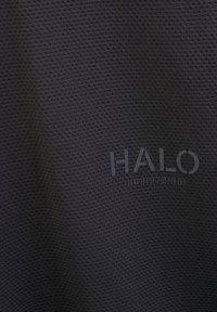 Czarna tkanina o fakturze przedstawia wzór małych wypukłych kwadratów. Nazwa marki "HALO" jest wyraźnie tłoczona w dolnej części.