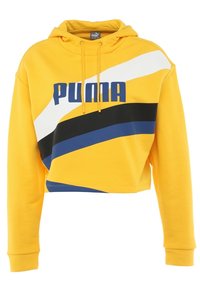 Žlutá zkrácená mikina s klokankou, zdobená výraznými černými, modrými a bílými diagonálními pruhy a modrým logem "PUMA" na hrudi.