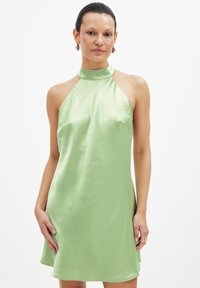 Grön satin halterneck-klänning med en lös passform, slät textur och sidoflikar. Designad för en knälång silhuett.