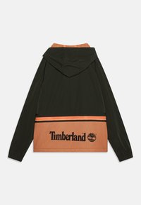 Giacca nera e arancione con cappuccio, caratterizzata da una sezione inferiore in rete e il logo "Timberland" in nero su uno sfondo arancione a contrasto.