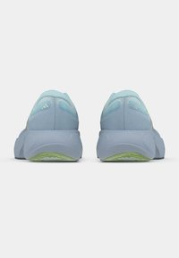 Αθλητικά παπούτσια ανοιχτού γαλάζιου χρώματος με υφασμάτινη επάνω επιφάνεια, μαλακή σόλα και πράσινη λεπτομέρεια στην εξωτερική σόλα. Οπίσθια όψη που δείχνει ομαλό, στρογγυλεμένο σχεδιασμό.
