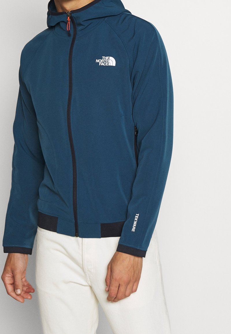 Granatowa bluza z kapturem na zamek, wykonana z miękkiego materiału. Posiada biały logotyp, elastyczne mankiety i sznurek do regulacji kaptura.