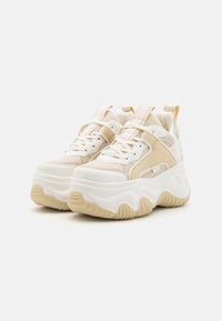 Adidași voluminoși într-o nuanță crem și bej, având un superiores din plasă, limbă căptușită și o talpă din cauciuc texturată cu un design ondulat.