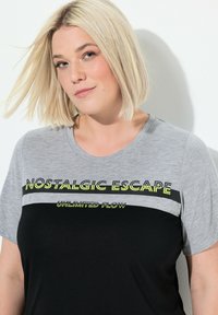 Tričko s kr�átkým rukávem s šedou horní částí, černou dolní částí a neonově žlutým textem "NOSTALGIC ESCAPE" a "UNLIMITED FLOW."