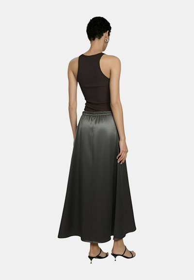 Top a fascia nera a costine abbinato a una lunga gonna in satin grigio scuro con una vita elastica. L'outfit è completato da tacchi neri.