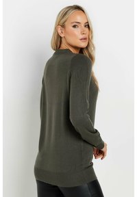 Maglione lungo verde oliva a maniche lunghe con scollatura rotonda, morbida consistenza a maglia e polsini e orlo a costine. La vista posteriore mostra una vestibilità rilassata.