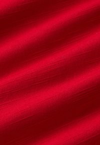 Tejido texturizado rojo con una superficie suave, con sutiles patrones lineales y un tono rico, adecuado para diversas aplicaciones textiles.