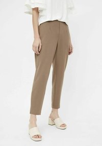 Bruine op maat gemaakte broek van zachte stof, met een taps toelopende pijp en een gladde textuur. Gecombineerd met nude block-heeled sandalen.