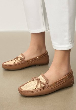 Barna bőrből készült mokaszinok fonott világosbarna díszítéssel, aranyszínű fém részekkel és dekoratív masni részlettel. Alkalmasak hétköznapi viseletre, lapos talppal.