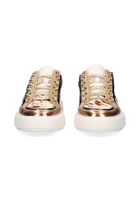 Par de zapatillas con suelas blancas, punteras metálicas en bronce, paneles en beige y negro, tela de estampado animal y tachuelas de cristal decorativas a lo largo de los cordones.