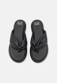 Sandales à glissière en cuir noir avec un design de sangle nouée, texture douce et semelle incurvée pour le confort.