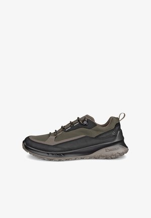 Zapatilla de senderismo baja de color verde oscuro y negro con cordones estampados, lengüeta en el talón y suela resistente con marca Michelin.