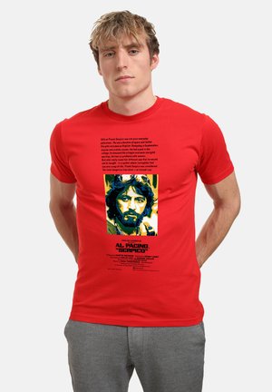 Rød bomulds t-shirt med grafisk print af Al Pacino fra "Serpico," med tekst nedenfor i sort. Korte ærmer, tætsiddende design.