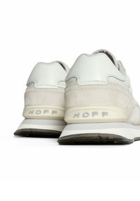 Sneaker bianche e grigie chiare con dettagli in camoscio, forme curve, suole imbottite e il marchio "HOFF" sulla maniglia posteriore.