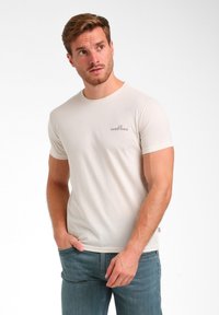 Hellbeige Kurzarm-T-Shirt aus Baumwolle mit einem runden Halsausschnitt und einem kleinen gestickten Logo auf der Brust.