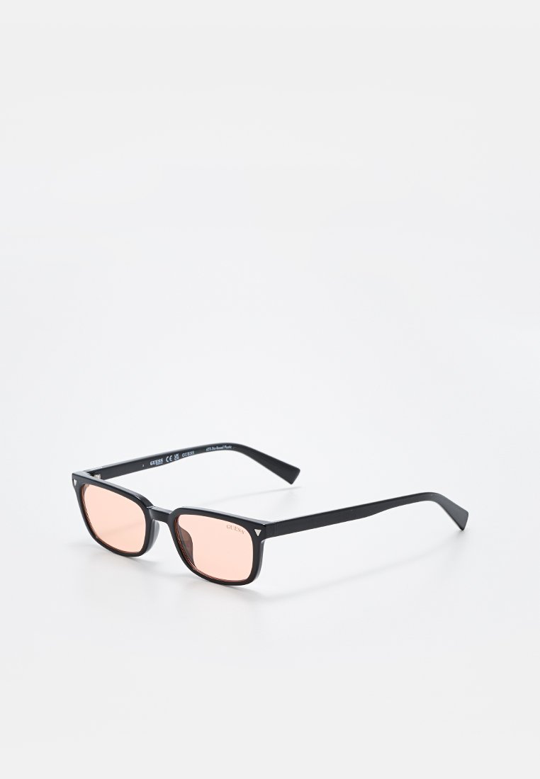 Czarne okulary przeciwsłoneczne z prostokątnymi oprawkami, jasnoróżowymi soczewkami i fakturowanym wykończeniem na zausznikach. Minimalistyczny design z eleganckimi liniami.