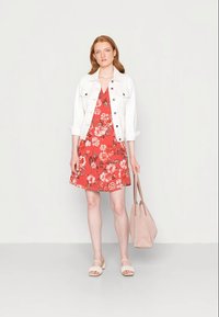 Vestido floral vermelho com decote em V e saia rodada, por baixo de uma jaqueta de ganga branca. Usado com sandálias creme e uma mala de tote rosa-claro.
