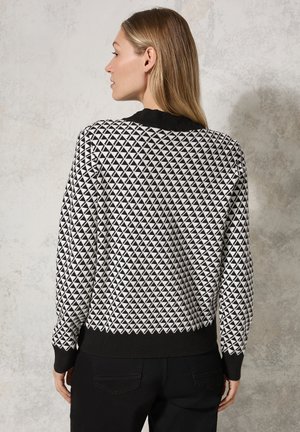 Pull noir et blanc avec un motif géométrique en triangle, col et poignets côtelés noirs, et une coupe classique. Tissu tricoté texturé.