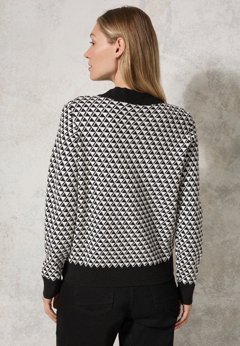 Maglione bianco e nero con un motivo geometrico a triangolo, colletto e polsini a coste neri e una vestibilità classica. Tessuto in maglia testurizzata.