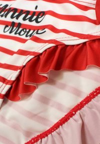 Tissu rayé rouge et blanc avec des bords froncés. Texte "Minnie Mouse" en noir en haut. Texture douce et finition lisse. Multiples couches.