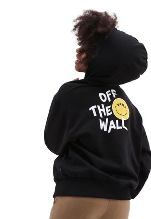 Hoodie noir en coton, avec un grand texte graphique blanc "OFF THE WALL" et un logo de smiley jaune au dos.