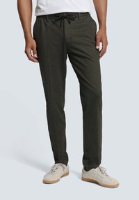 Dark green, lightweight jogger pants with an elastic drawstring waistband, side pockets, and a smooth texture. Worn with cream sneakers.