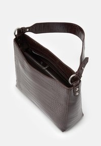 Krokotiilin kuvioitu ruskea nahkalaukku irrotettavalla hihnalla, vetoketjusuljenta ja sisätasku, esittelee jämäkän suorakulmaisen muodon.