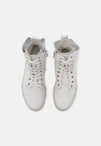 Botas de tobillo de cuero blanco con cordones, cremallera lateral, collar acolchado y suela de goma. Textura suave con costuras mínimas y acentos de hardware en plata.