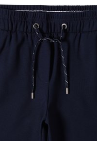 Námořnické modré jogger kalhoty s elastickým pasem, nastavitelnou šňůrkou a kovovými kroužky. Hladká textura bez viditelných vzorů.
