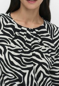 Mustavalkoinen zebra-raita-toppi, jossa on pleat-detailit kaula-aukolla, valmistettu pehmeästä, kevyestä kankaasta, joka sopii hyvin arkikäyttöön.