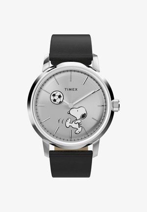 Ronde zilveren Timex-horloge met zwarte leren band, met Snoopy die een voetbal trapt op een lichtgrijze wijzerplaat met eenvoudige uurmarkeringen.