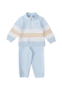 Chándal de color azul claro con una camiseta de media cremallera que presenta rayas horizontales en beige y blanco. Material suave, puños acanalados y rayas laterales en los pantalones.