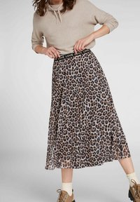 Hame leopard-kuosisella, jossa on musta joustava vyötärö, johon on kirjailtu "LOVE"-teksti. Midimittainen, valuva kangas, yhdistettynä vaaleanbeigeihin jalkineisiin ja kermaisiin sukkiin.