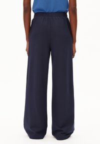 Marinblå vida byxor med elastisk midja. Tillverkade av mjukt tyg, med en slät yta och en avslappnad passform. Inga synliga fickor.