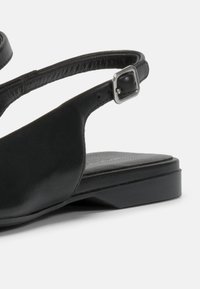 Sandale noire en cuir lisse, design ouvert à l'avant, avec une bride ajustable à la cheville et une boucle en argent ; petit talon carré.