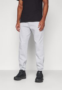 Grå bomulds sweatpants med elastisk talje og manchetter, parret med sorte vandresko med tekstureret sål og snørebånd.