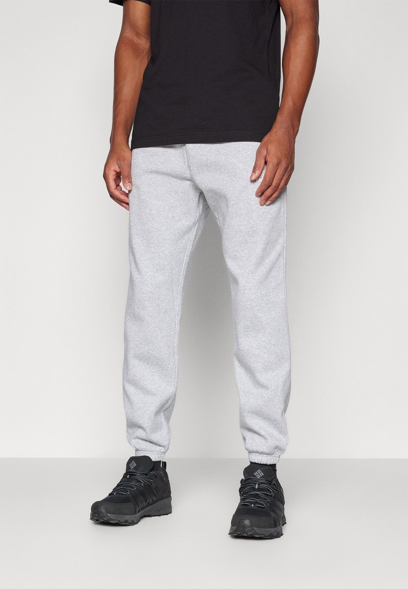 Grå bomulds sweatpants med elastisk talje og manchetter, parret med sorte vandresko med tekstureret sål og snørebånd.