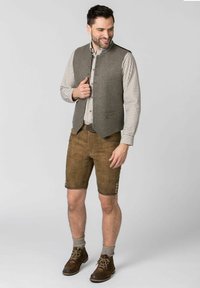 Braune Lederhosen mit Seitenschaltern, eine graue Wollweste und ein kariertes Hemd. Braune Schnürstiefel und graue knielange Socken runden das Outfit ab.