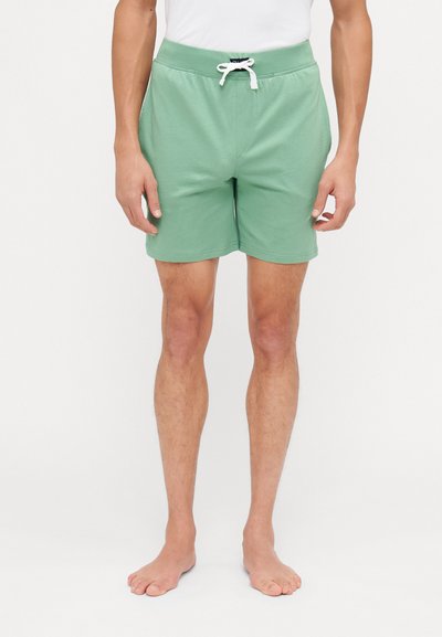 Pantaloni corti verdi in cotone con cintura elastica, cordoncino bianco e design semplice. Presentano una vestibilità ampia e lunghezza fino a metà coscia.