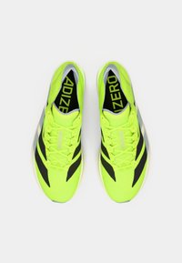 Zapatillas de running de color amarillo neón con acentos negros, que presentan un diseño elegante, parte superior texturizada y cordones. Logo "ADIZERO" visible en la lengüeta.