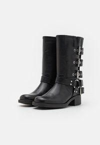 Svarta ankelstövlar i läder med rundad tå, staplad klack och flera silverfärgade spänndetaljer längs sidan. Jämn och slät yta över hela skon.