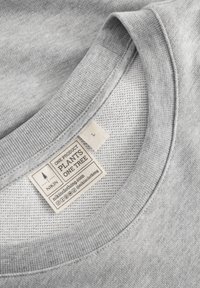 Hellgrau sweatshirt mit rundem Halsausschnitt, strukturierter Stoff und einem Etikett, das die Größe L und umweltfreundliche Merkmale anzeigt.