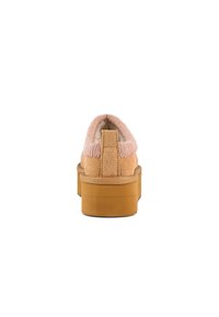 Zadný pohľad na ružovú slip-on obuv z nubuku s mäkkým golierom, pevným hnedým podrážkou a textúrovaným povrchom. Obsahuje zadný úchyt pre jednoduché obúvanie.