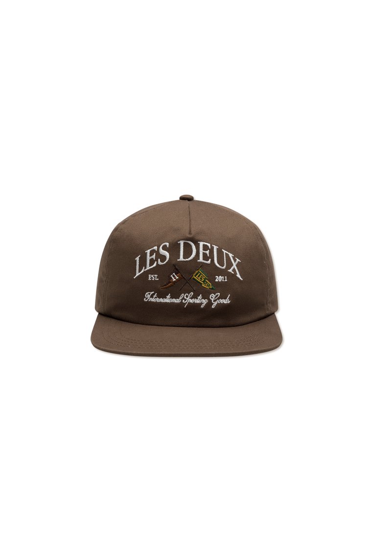 Barna snapback sapka, amely textilből készült; fehér hímzett feliratai vannak: "LES DEUX" és "International Sporting Goods", grafikai kiegészítőkkel.