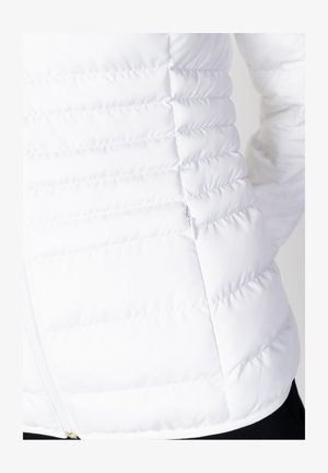 Witte pufferjack met een doorgestikt ontwerp, voorzien van horizontale stiksels, een zijrits en een gladde textuur. Geschikt voor koud weer.