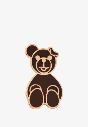 Aksesuaras, primenantis rudąjį lokį, su blizgiu paviršiumi. Jame yra rožinio aukso apvadas ir kaspinėlis ant lokio galvos. Kompaktiškas dizainas.